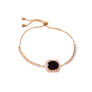 Adjustable gold bracelet with oval purple gemstone and cubic zirconia accents on white background