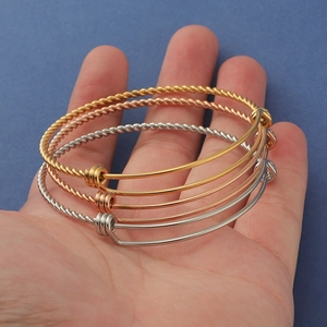 Detailed view of three-color twisted metal bracelets in gold, rose gold and silver finishes