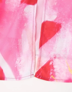 Détail du tissu à imprimé abstrait rose et rouge avec couture fine et fente latérale