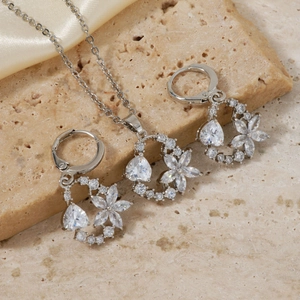 Detail of elegant silver jewelry set featuring floral and teardrop cubic zirconia accents