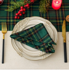 Detail of green plaid napkin on beige ceramic plate with festive holiday decorations