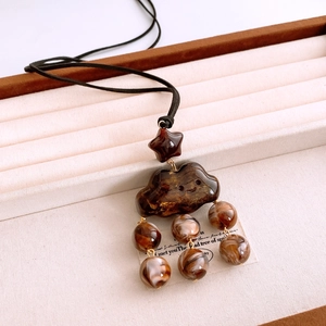 Detail of resin cloud charm with engraved smiley face and amber star on beaded necklace