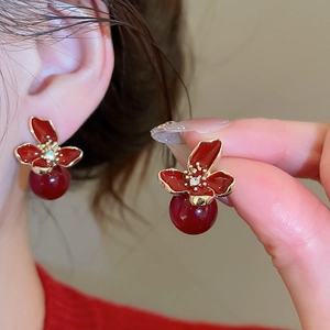 Detail of red flower petal earrings with gold edges and hanging red pearl beads