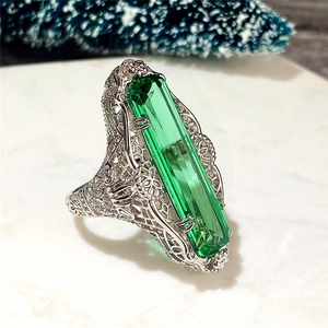 Gros plan d'un zircon vert taille émeraude serti dans un anneau argenté de style rétro