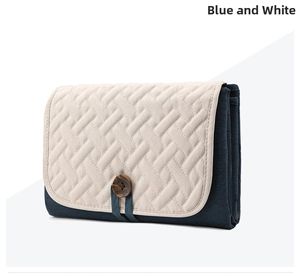 Foldable baby changing mat in blue and white with quilted texture and wooden button