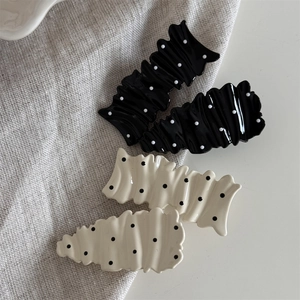 Black and cream polka dot ruffled hair clips set of four on minimalist linen background