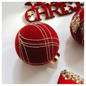 Macro shot of red velvet Christmas ball with gold glitter lines and metallic hook
