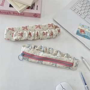 Close-up of cream floral canvas pencil case and matching headband on a white desk