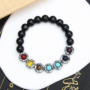 Detailed close-up of tiger eye yoga bracelet with seven chakra energy beads on a white pad