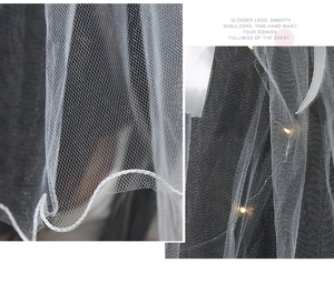 Detailed macro view of white wedding veil featuring warm LED lights and honeycomb mesh texture
