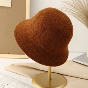 Elegant brown knitted wool bucket hat for women on a gold stand, minimalist style