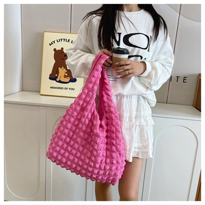 Close-up of pink puff pleated handbag featuring unique bubble texture and soft strap