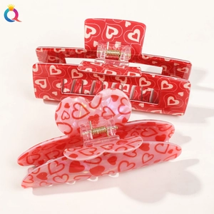Close-up of red acrylic hair clips with heart patterns on a white background