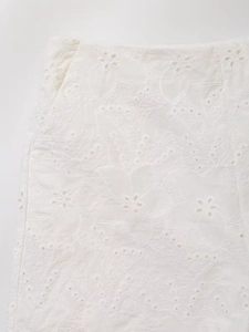Detailed close-up of intricate white floral hollow-out embroidery on fabric