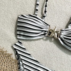 Detail of striped bikini top featuring a golden starfish metal buckle on fabric