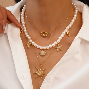 Bohemian layered gold necklace set with sea shell starfish charms and pearls on a model