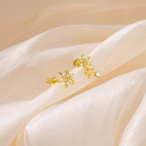Detailed macro view of gold flower earrings with pavé white zircon stones on silk
