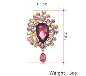 Close-up of luxury crystal brooch with purple pear-shaped stone and gold-tone metal detail