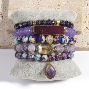 Detail of five-piece Bohemian beaded bracelet set with purple stones and gold charms