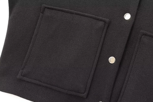 Macro shot of black wool jacket featuring square patch pocket and silver metal buttons