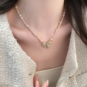Detailopname van elegante parelketting met zirkonia strikhanger gedragen door model