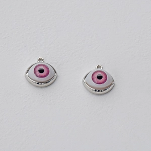 Detailed view of silver alloy pendants with realistic pink eye charms and metal loops