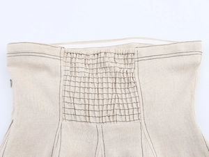 Détail de haut en lin beige avec surpiqûres noires et taille élastiquée froncée