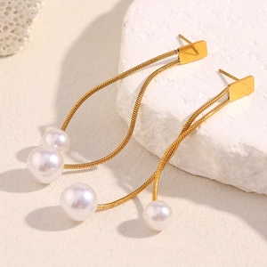 Detailed macro view of 18K gold plated tassel earrings with white pearls on a stone