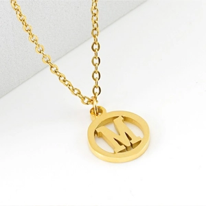 Détail d'un collier en acier inoxydable doré 18 carats avec pendentif lettre M évidé