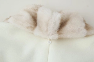 Detail shot of the cream faux fur collar and white resin button on a wool coat