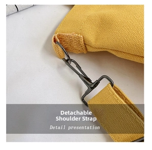 Detail view of the yellow canvas bag featuring a black matte detachable shoulder strap hook