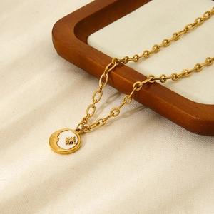 18K gold plated stainless steel necklace with sun and moon shell pendant on wooden tray