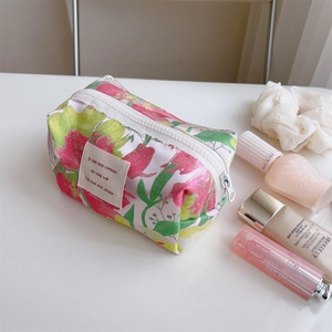 Close-up of pink floral jacquard makeup bag with white zipper and chic woven label