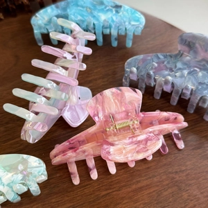 Primo piano di fermagli per capelli in acetato marmorizzato con trame colorate su legno