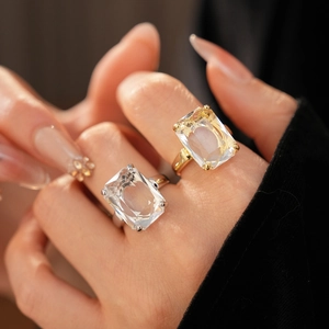 Detail view of large emerald-cut zircon rings in gold and silver finish on hand