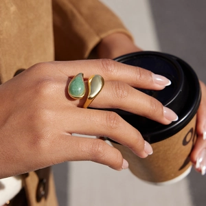 Goldener offener Ring mit grünem Aventurin getragen von Model mit Kaffeetasse