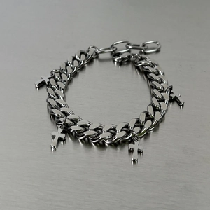 Silver stainless steel Cuban chain bracelet with multiple cross pendants on metallic surface