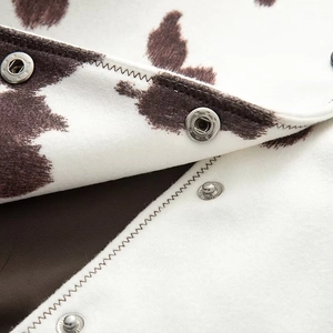 Detail of jacket showing cow print fabric and star-shaped silver metallic snap button