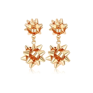 Detailed close-up of golden metallic flower bow earrings with a mirrored reflection