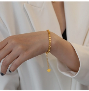 Dettaglio dell'elegante bracciale in oro 18 carati con ciondolo a cuore sul polso di una donna