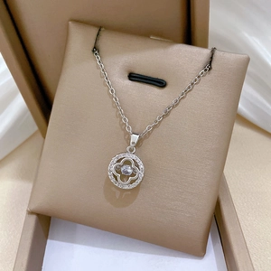 Macro shot of silver clover pendant with embedded crystals in a golden jewelry box