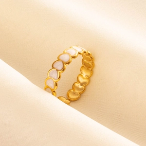 Detailed shot of golden heart enamel rings displayed on elegant beige silk fabric