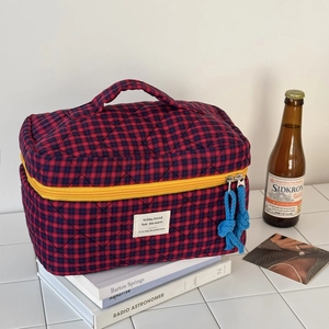 Close-up of quilted red and blue checkered cosmetic bag with yellow zipper and top handle