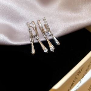 Detail view of silver drop C-shaped earrings with sparkling cubic zirconia on silk