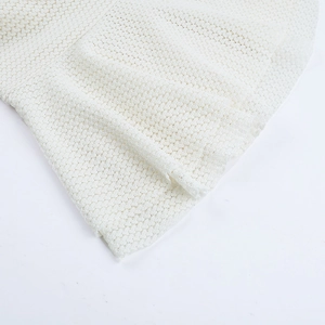 Close-up of white knitted mesh fabric texture and hollow-out detailing on summer dress