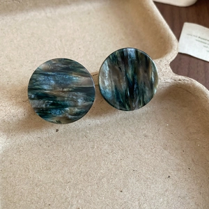 Vue macro détaillée de boucles d'oreilles rondes en acrylique avec texture de marbre vert