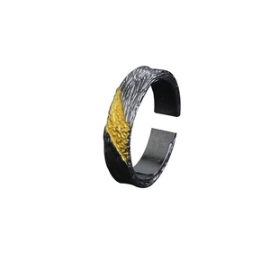 Detail of vintage silver, black and gold tricolor ring with lava rock texture surface