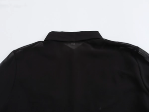 Detailed flat lay of black chiffon shirt showing professional collar and fabric texture