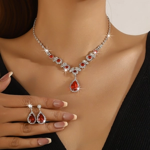 Macro detail of bridal teardrop necklace and earrings with red stones and crystals