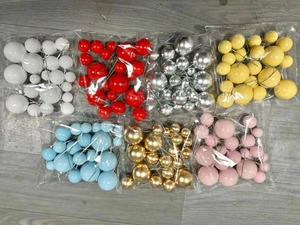 Assorted colorful foam ball cake toppers in seven bags on a grey wooden surface
